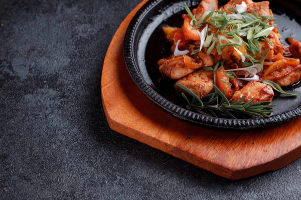 stock image Hot frying pan with pieces of fried meat in caramelized sauce. Cooked and fresh vegetables as garnish and garnish.