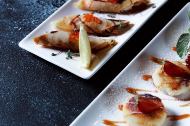 Kırmızı somon havyarlı krep. Koyu mavi arka planda güzel bir yemek servisi. Restoran tatlı menüsü.