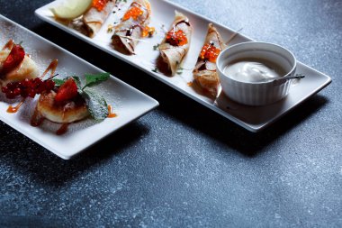 Kırmızı somon havyarlı krep. Koyu mavi arka planda güzel bir yemek servisi. Restoran tatlı menüsü.