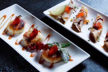 Kırmızı somon havyarlı krep. Koyu mavi arka planda güzel bir yemek servisi. Restoran tatlı menüsü.