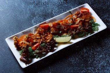 Sebze yahnisi. Bir restoranda haşlanmış sebze servis edilir. Koyu mavi arka planda beyaz plaka.