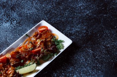 Sebze yahnisi. Bir restoranda haşlanmış sebze servis edilir. Koyu mavi arka planda beyaz plaka.