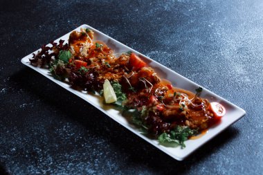 Sebze yahnisi. Bir restoranda haşlanmış sebze servis edilir. Koyu mavi arka planda beyaz plaka.