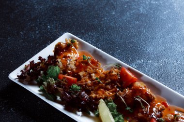 Sebze yahnisi. Bir restoranda haşlanmış sebze servis edilir. Koyu mavi arka planda beyaz plaka.