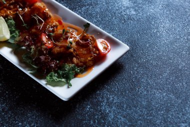 Sebze yahnisi. Bir restoranda haşlanmış sebze servis edilir. Koyu mavi arka planda beyaz plaka.