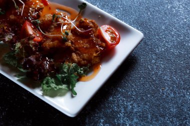 Sebze yahnisi. Bir restoranda haşlanmış sebze servis edilir. Koyu mavi arka planda beyaz plaka.