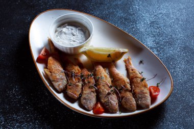 Kral balık büyük beyaz bir tabakta. Hamurda kızartılmış balık ve güzel bir sunum. Koyu mavi arka planda pişirilmiş deniz ürünleri..