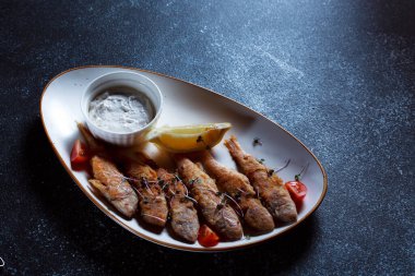 Kral balık büyük beyaz bir tabakta. Hamurda kızartılmış balık ve güzel bir sunum. Koyu mavi arka planda pişirilmiş deniz ürünleri..
