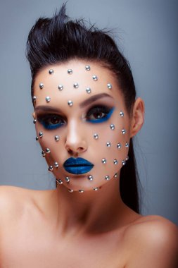 Güzellik tarzında makyaj. Parlak dudaklar ve gözler. Güzel bir genç kızın portresi. Günlük detaylı cilt rötuşları. Etkileyici kaşlar. Kocaman kirpikleri var. Neon gölgeleri.