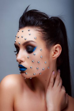 Güzellik tarzında makyaj. Parlak dudaklar ve gözler. Güzel bir genç kızın portresi. Günlük detaylı cilt rötuşları. Etkileyici kaşlar. Kocaman kirpikleri var. Neon gölgeleri.