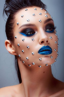 Güzellik tarzında makyaj. Parlak dudaklar ve gözler. Güzel bir genç kızın portresi. Günlük detaylı cilt rötuşları. Etkileyici kaşlar. Kocaman kirpikleri var. Neon gölgeleri.