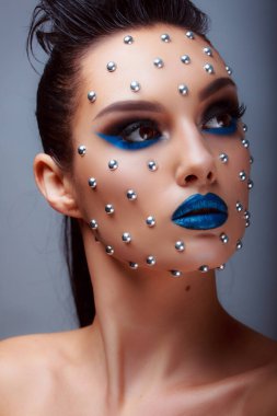 Güzellik tarzında makyaj. Parlak dudaklar ve gözler. Güzel bir genç kızın portresi. Günlük detaylı cilt rötuşları. Etkileyici kaşlar. Kocaman kirpikleri var. Neon gölgeleri.