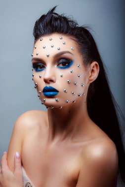 Güzellik tarzında makyaj. Parlak dudaklar ve gözler. Güzel bir genç kızın portresi. Günlük detaylı cilt rötuşları. Etkileyici kaşlar. Kocaman kirpikleri var. Neon gölgeleri.