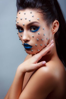 Güzellik tarzında makyaj. Parlak dudaklar ve gözler. Güzel bir genç kızın portresi. Günlük detaylı cilt rötuşları. Etkileyici kaşlar. Kocaman kirpikleri var. Neon gölgeleri.