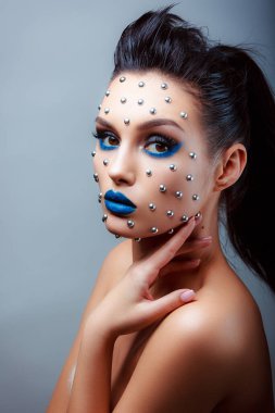 Güzellik tarzında makyaj. Parlak dudaklar ve gözler. Güzel bir genç kızın portresi. Günlük detaylı cilt rötuşları. Etkileyici kaşlar. Kocaman kirpikleri var. Neon gölgeleri.