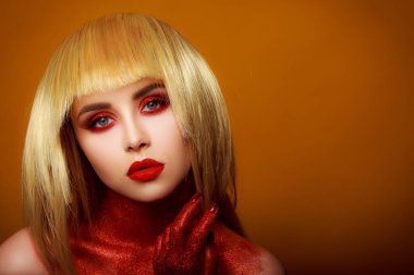 Güzellik tarzında kırmızı makyaj. Parlak dudaklar ve gözler. Güzel bir genç kızın portresi. Günlük detaylı cilt rötuşları. Etkileyici kaşlar. Kocaman kirpikleri var. Neon gölgeler. Sarı saç rengi. .