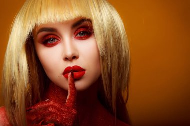 Güzellik tarzında kırmızı makyaj. Parlak dudaklar ve gözler. Güzel bir genç kızın portresi. Günlük detaylı cilt rötuşları. Etkileyici kaşlar. Kocaman kirpikleri var. Neon gölgeler. Sarı saç rengi. .