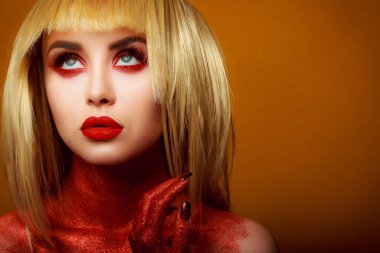 Güzellik tarzında kırmızı makyaj. Parlak dudaklar ve gözler. Güzel bir genç kızın portresi. Günlük detaylı cilt rötuşları. Etkileyici kaşlar. Kocaman kirpikleri var. Neon gölgeler. Sarı saç rengi. .