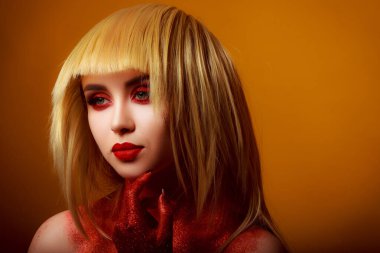 Güzellik tarzında kırmızı makyaj. Parlak dudaklar ve gözler. Güzel bir genç kızın portresi. Günlük detaylı cilt rötuşları. Etkileyici kaşlar. Kocaman kirpikleri var. Neon gölgeler. Sarı saç rengi. .