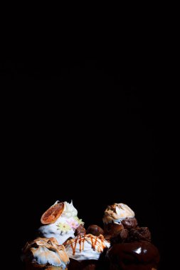 Celebratory cupcakes on a dark background. Festive baked goods with exuberant spring colors on a dark background. Variety of Easter cakes. Free space for an inscription.