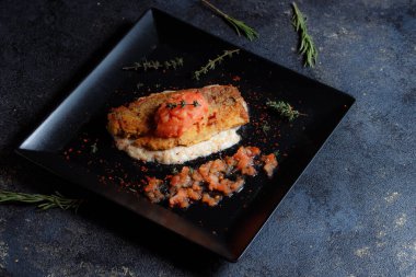 Izgara somon bifteği, taze domates, biber tohumu, biberiye, siyah tabakta kekik..