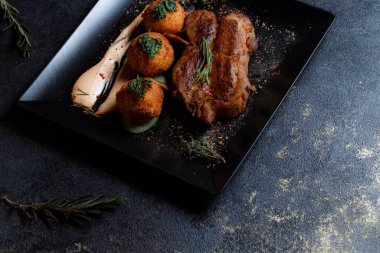 Karamelli soslu hindi bifteği ve siyah tabakta patates köftesi. Baharatlar - biber, maydanoz, fesleğen, kekik, beyaz sarımsak sosu.