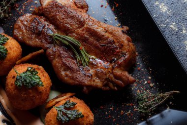 Karamelli soslu hindi bifteği ve siyah tabakta patates köftesi. Baharatlar - biber, maydanoz, fesleğen, kekik, beyaz sarımsak sosu.