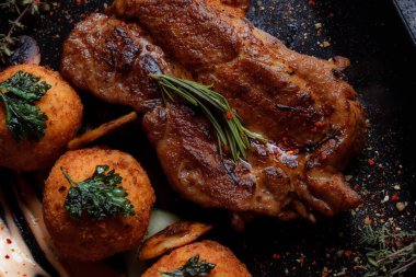 Karamelli soslu hindi bifteği ve siyah tabakta patates köftesi. Baharatlar - biber, maydanoz, fesleğen, kekik, beyaz sarımsak sosu.