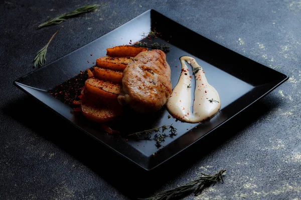 Baharatlı ızgara tavuk bifteği ve siyah bir tabakta fırında patates fotokopi alanı olan koyu dokulu bir arka planda..