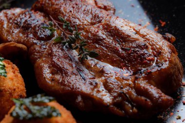 Karamelli soslu hindi bifteği ve siyah tabakta patates köftesi. Baharatlar - biber, maydanoz, fesleğen, kekik, beyaz sarımsak sosu.