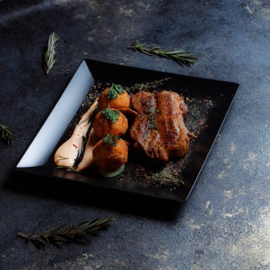 Karamelli soslu hindi bifteği ve siyah tabakta patates köftesi. Baharatlar - biber, maydanoz, fesleğen, kekik, beyaz sarımsak sosu.