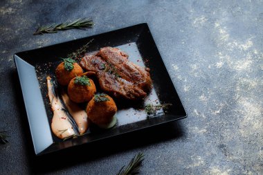Karamelli soslu hindi bifteği ve siyah tabakta patates köftesi. Baharatlar - biber, maydanoz, fesleğen, kekik, beyaz sarımsak sosu.