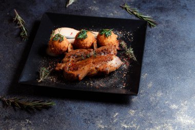 Karamelli soslu hindi bifteği ve siyah tabakta patates köftesi. Baharatlar - biber, maydanoz, fesleğen, kekik, beyaz sarımsak sosu.