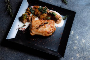 Sebzeli biftek ve siyah tabakta ızgara mantar. Baharatlar - biber, maydanoz, fesleğen, kekik, beyaz sarımsak sosu. Kızarmış etin detaylı dokusu.