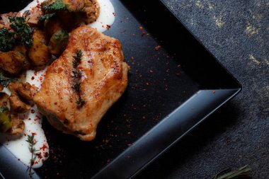 Sebzeli biftek ve siyah tabakta ızgara mantar. Baharatlar - biber, maydanoz, fesleğen, kekik, beyaz sarımsak sosu. Kızarmış etin detaylı dokusu.