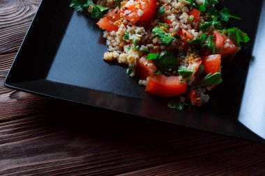 Yeşil yapraklı ve sebzeli salata. Lean vejetaryen yemeği. Hafif salata, domatesli marul, bulgur, maydanoz, baharatlı susam tohumu..