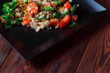 Yeşil yapraklı ve sebzeli salata. Lean vejetaryen yemeği. Hafif salata, domatesli marul, bulgur, maydanoz, baharatlı susam tohumu..