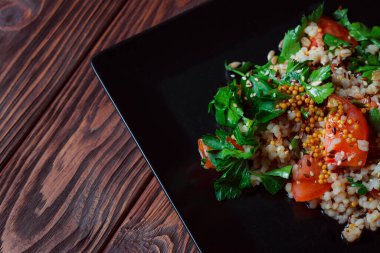 Yeşil yapraklı ve sebzeli salata. Lean vejetaryen yemeği. Hafif salata, domatesli marul, bulgur, maydanoz, baharatlı susam tohumu..
