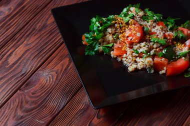 Yeşil yapraklı ve sebzeli salata. Lean vejetaryen yemeği. Hafif salata, domatesli marul, bulgur, maydanoz, baharatlı susam tohumu..
