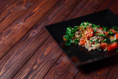 Yeşil yapraklı ve sebzeli salata. Lean vejetaryen yemeği. Hafif salata, domatesli marul, bulgur, maydanoz, baharatlı susam tohumu..