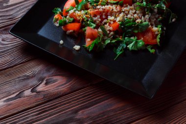 Yeşil yapraklı ve sebzeli salata. Lean vejetaryen yemeği. Hafif salata, domatesli marul, bulgur, maydanoz, baharatlı susam tohumu..