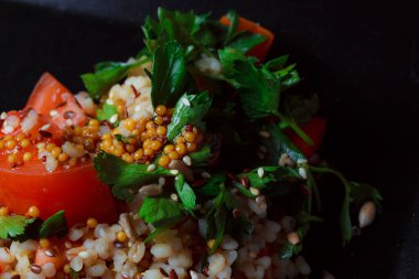Salad with green leaves and vegetables. Lean vegetarian dish. Light salad organic mix lettuce with tomatoes, bulgur, parsley, seasoned roasted sesame seeds.