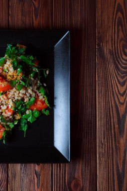 Yeşil yapraklı ve sebzeli salata. Lean vejetaryen yemeği. Hafif salata, domatesli marul, bulgur, maydanoz, baharatlı susam tohumu..