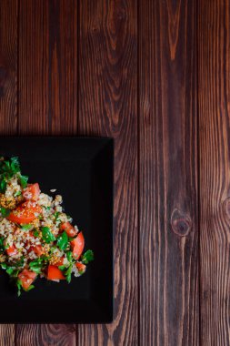 Yeşil yapraklı ve sebzeli salata. Lean vejetaryen yemeği. Hafif salata, domatesli marul, bulgur, maydanoz, baharatlı susam tohumu..