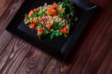 Yeşil yapraklı ve sebzeli salata. Lean vejetaryen yemeği. Hafif salata, domatesli marul, bulgur, maydanoz, baharatlı susam tohumu..