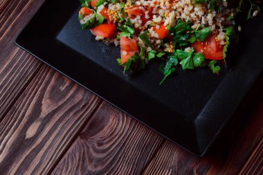 Yeşil yapraklı ve sebzeli salata. Lean vejetaryen yemeği. Hafif salata, domatesli marul, bulgur, maydanoz, baharatlı susam tohumu..