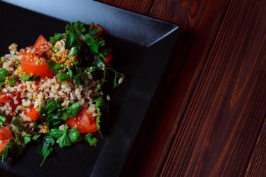 Yeşil yapraklı ve sebzeli salata. Lean vejetaryen yemeği. Hafif salata, domatesli marul, bulgur, maydanoz, baharatlı susam tohumu..