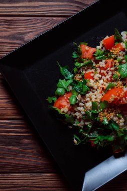 Yeşil yapraklı ve sebzeli salata. Lean vejetaryen yemeği. Hafif salata, domatesli marul, bulgur, maydanoz, baharatlı susam tohumu..
