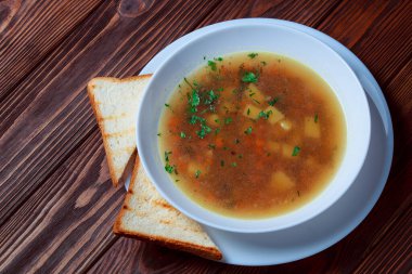 Tahta tepside ekmekle sebze çorbası. Koyu renk tahta arka planda beyaz kase. Üst Manzara. Boşluğu kopyala.