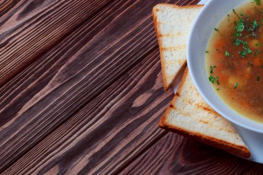 Tahta tepside ekmekle sebze çorbası. Koyu renk tahta arka planda beyaz kase. Üst Manzara. Boşluğu kopyala.